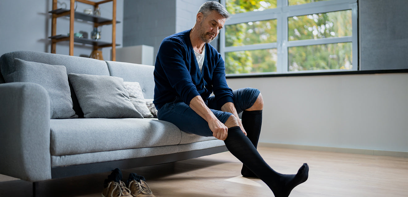 Man sitting on a couch putting on socks in a modern living room.