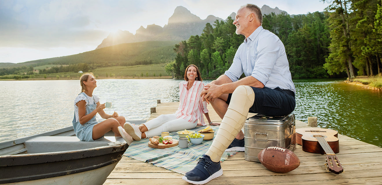 Family sitting on a dock by a lake with mountains in the background